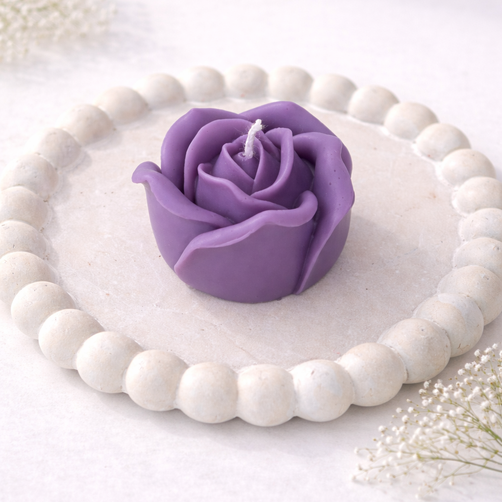 Vela decorativa RosaVela decorativa Rosa XL Eirèa de soja escultórica color lila sobre bandeja blanca XL Eirèa de soja escultórica color morado sobre base redonda